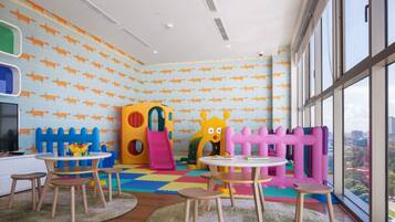 A children's play area with colorful play structures, a large window, and a view of the city.