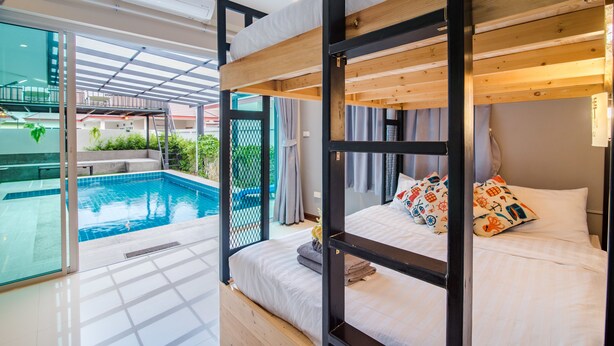 Quarto de hotel moderno com beliche, piscina privativa e porta de vidro que dá para uma varanda.