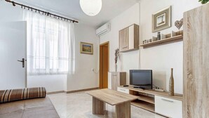 A modern living room with a sofa, a wooden coffee table, a TV, and built-in cabinets. - Holiday apartment with air conditioning and Internet (Savudrija)