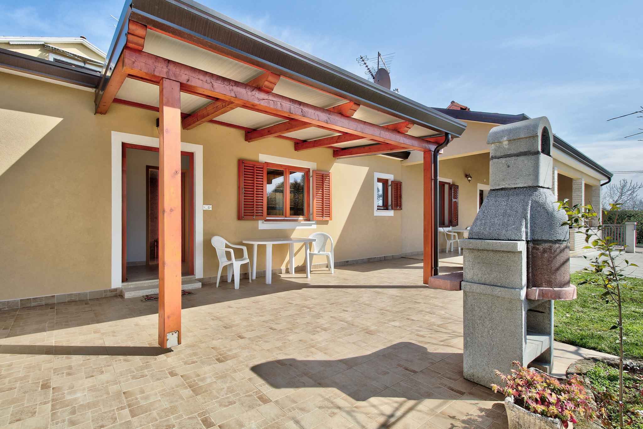 Un patio cubierto con una chimenea de piedra, sillas blancas y una mesa.