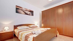A bedroom with a wooden bed, a nightstand, a wardrobe, and a wall-mounted picture. - Holiday apartment with air conditioning and Internet (Savudrija)
