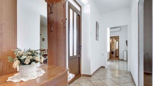 A hallway with a wooden reception desk, a white vase with flowers, and a door with a wooden frame. - Holiday apartment with air conditioning and Internet (Savudrija)