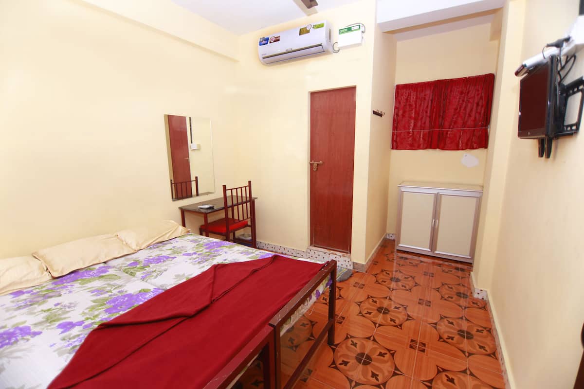 A bedroom with a bed, a desk, and a wardrobe.
