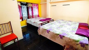 Ein Zimmer mit zwei Betten, einem Sessel und einem Fenster mit Vorhängen.
