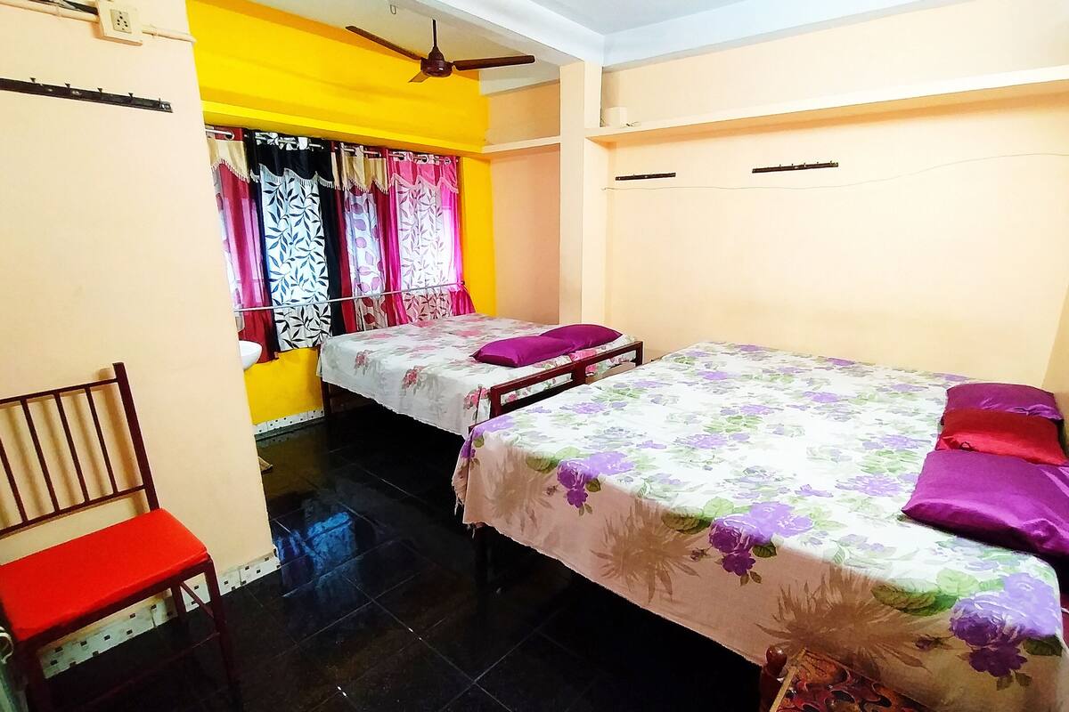 A room with two beds, a chair, and a window with curtains.