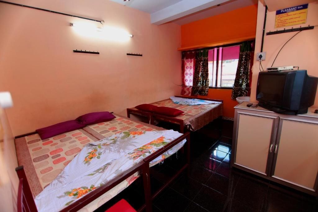A room with two beds, a television, and a cabinet.