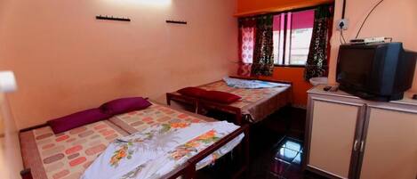 A room with two beds, a television, and a cabinet.