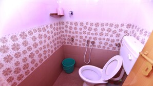 Ein kleines Badezimmer mit Toilette, Dusche und einem Eimer.