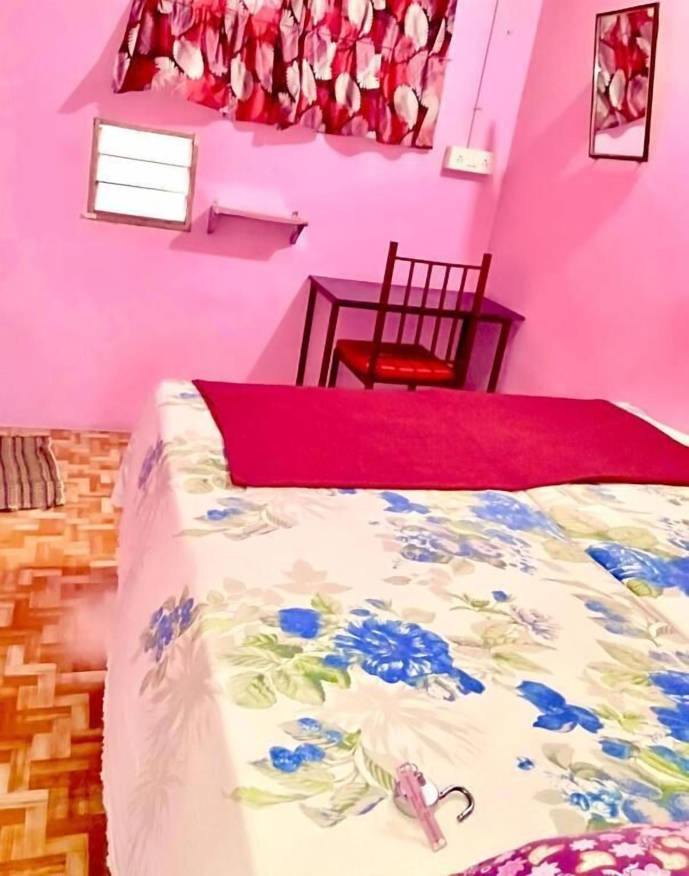 A bedroom with a bed, a chair, a window, and a wall-mounted air conditioner.