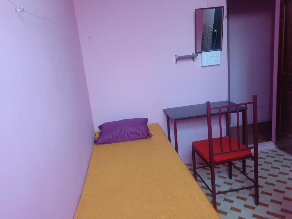 Una habitación pequeña con una cama individual, un escritorio y una silla.