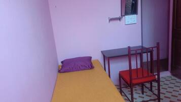 Una habitación pequeña con una cama individual, un escritorio y una silla.