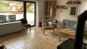 Ein geräumiges Wohnzimmer mit großem Fenster, Kamin, Sofa, Couchtisch und Bücherregal.