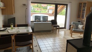 Ein Essbereich mit Tisch, Stühlen und Blick durch ein großes Fenster.