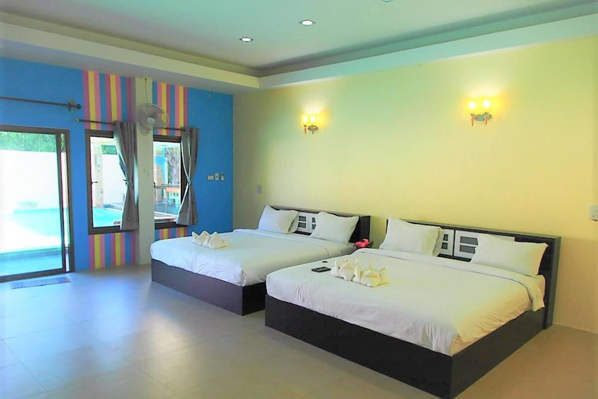 Habitación de hotel con dos camas, un ventanal con cortinas y vistas al exterior.