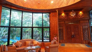 Una habitación con techo de madera curvada, ventanas amplias y puertas de madera tradicionales con intrincados grabados.