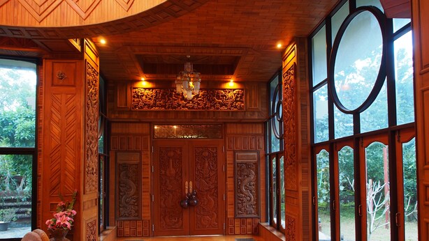 Un interior de madera con ventanas amplias, un candelabro y una puerta con detalles tallados.