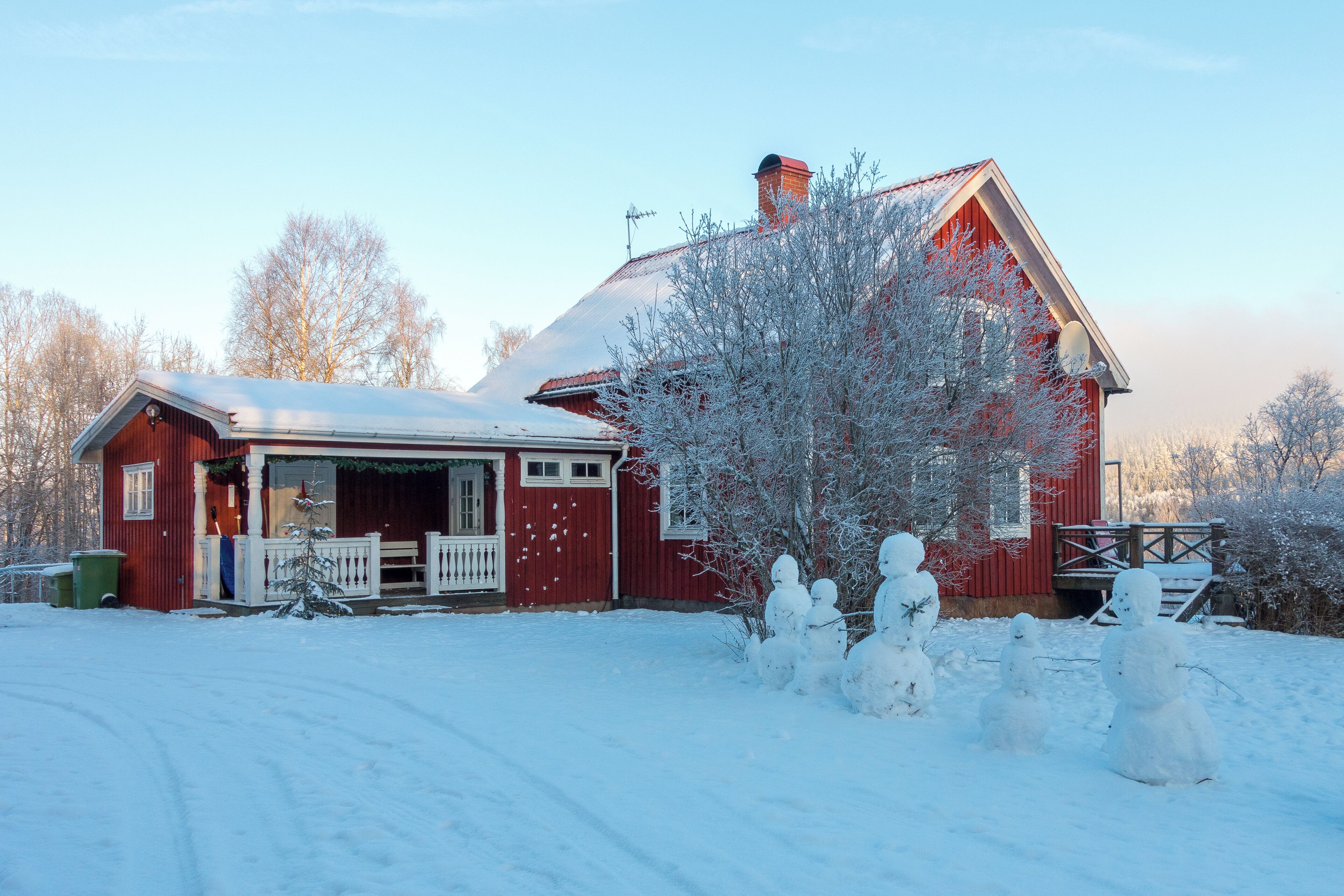 A red barn with a snow-covered roof and a white porch.