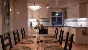 A modern kitchen with wooden cabinets, a dining table with chairs, and a vase with flowers.