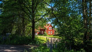 A red house surrounded by lush greenery and trees.