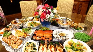 A table set with various dishes, including seafood, salads, and bread, surrounded by wicker chairs and a floral centerpiece. - Aiyara Garden Resort (Chanthaburi)