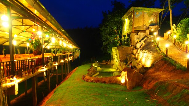 A nighttime outdoor area with a covered seating area, a small pool, and a rock formation. - Aiyara Garden Resort (Chanthaburi)