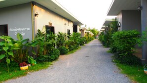 A pathway flanked by greenery and buildings with Thai signage. - Aiyara Garden Resort (Chanthaburi)