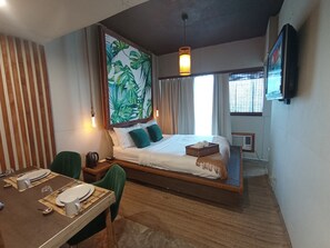 A modern hotel room with a large bed, a dining table set for two, and a large window with curtains. - The Staycation - Boutique rooms (Makati)