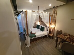 A bedroom with a bed, bedside table, chair, and a small table with a tray. - The Staycation - Boutique rooms (Makati)