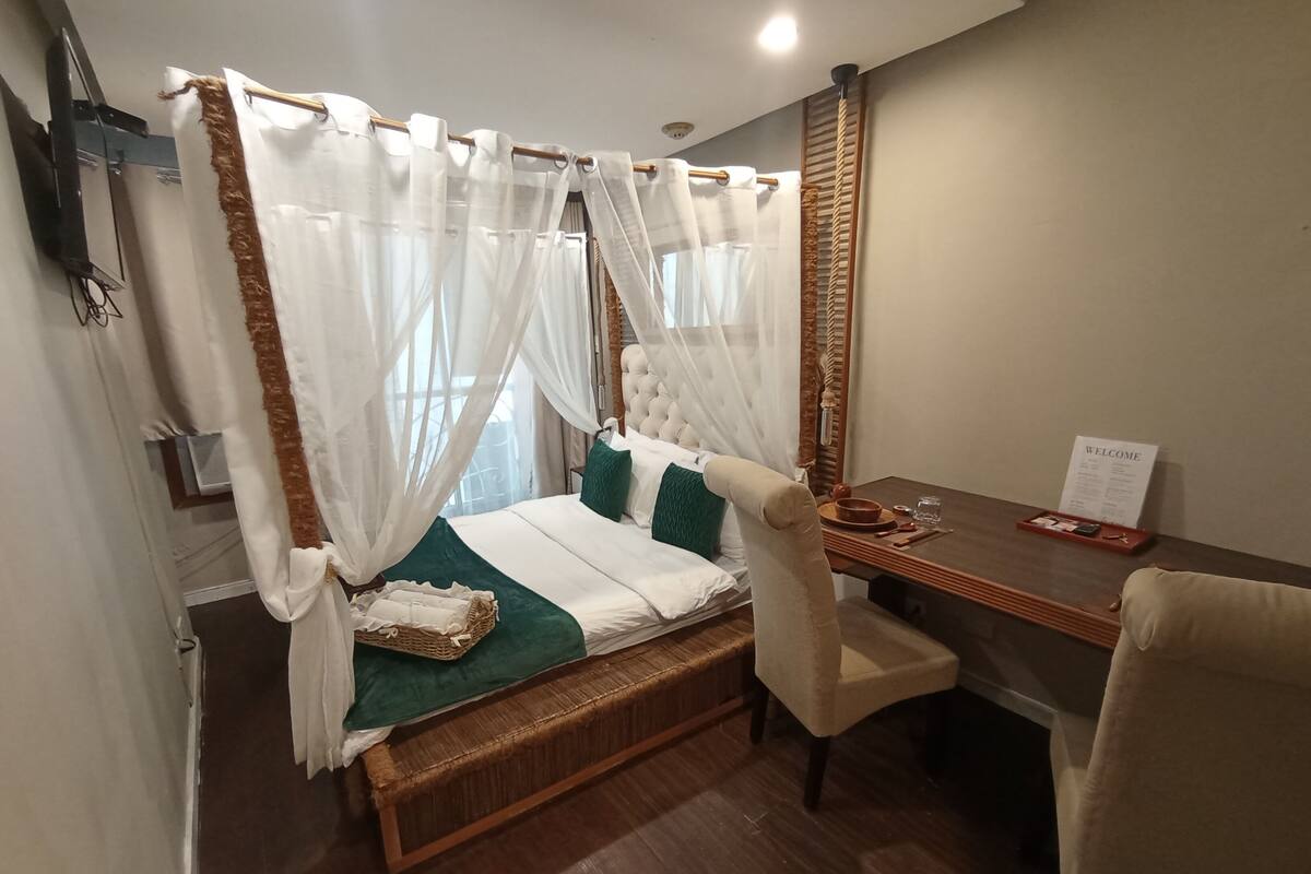 A bedroom with a four-poster bed, a wooden desk, and a chair.