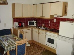 A compact kitchen with wooden cabinets, a microwave, a coffee maker, a sink, and a refrigerator. - Vacation apartment Jirkal - Holiday apartment (Obsthurn)