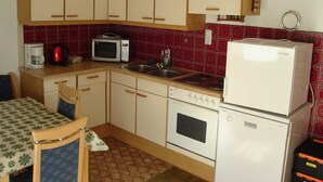 Una cocina compacta con electrodomésticos básicos, un comedor con mesa y sillas, y un suelo con diseño.