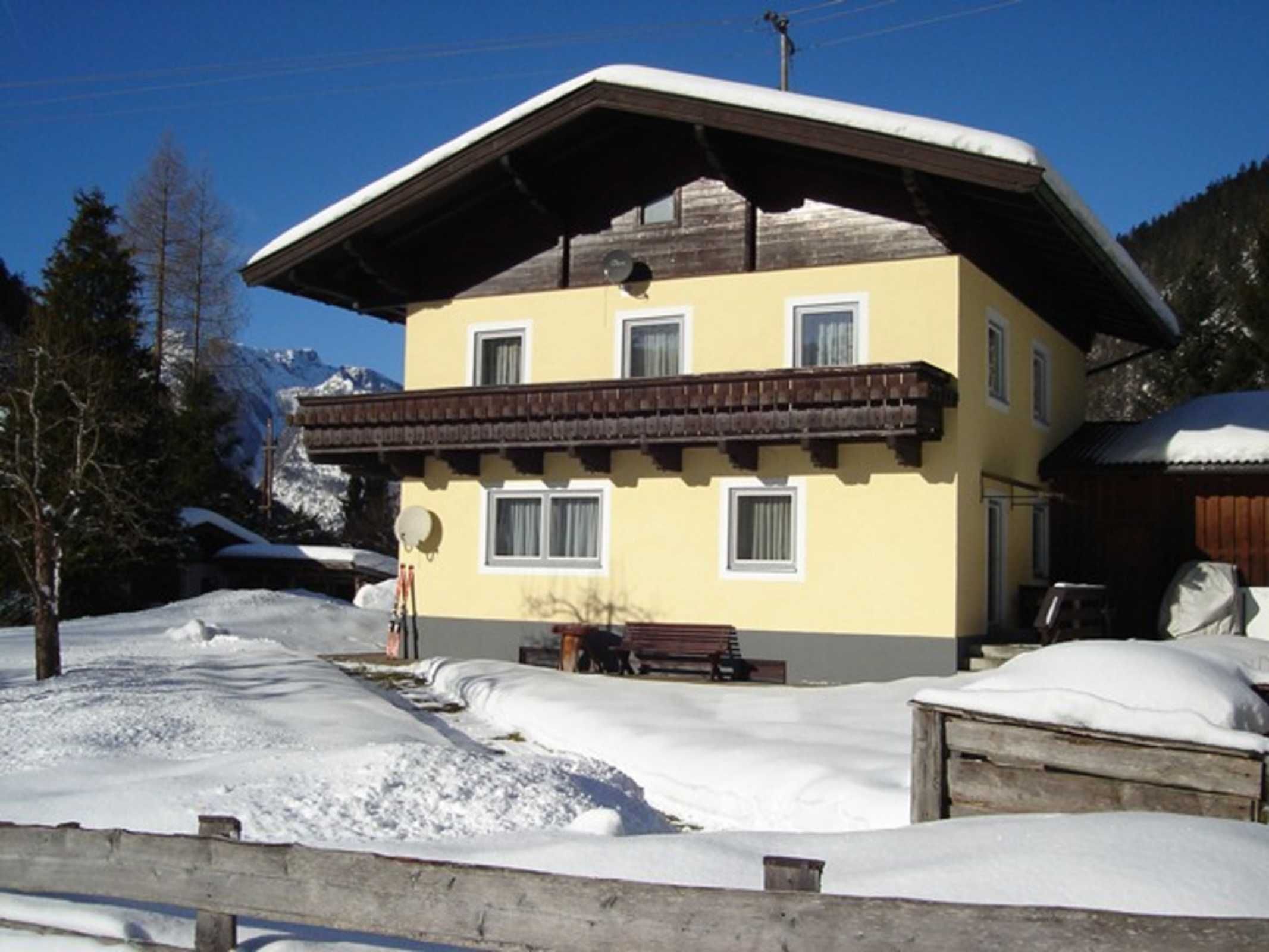 Um edifício de dois andares com varanda, rodeado por neve e montanhas.