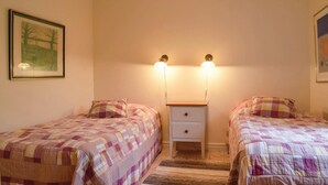 A bedroom with two beds, a nightstand, and wall-mounted lights. - 1 bedroom amazing home in Borgholm (Borgholm)