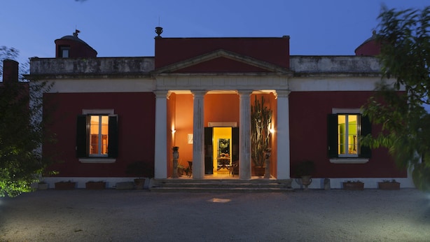 A building with a symmetrical facade, a central entrance with columns, and a red and white color scheme. - Villa Urso BedWine (Lecce)