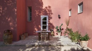 A courtyard with a table and chairs, potted plants, and a cactus. - Villa Urso BedWine (Lecce)
