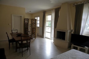 A room with a dining table, chairs, a television, a fireplace, and a view of the outdoors. - Villa Urso BedWine (Lecce)
