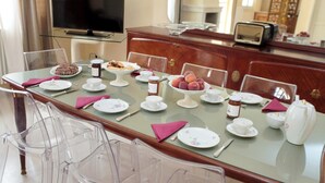 A dining table set with plates, cups, and a teapot, surrounded by clear chairs. - Villa Urso BedWine (Lecce)