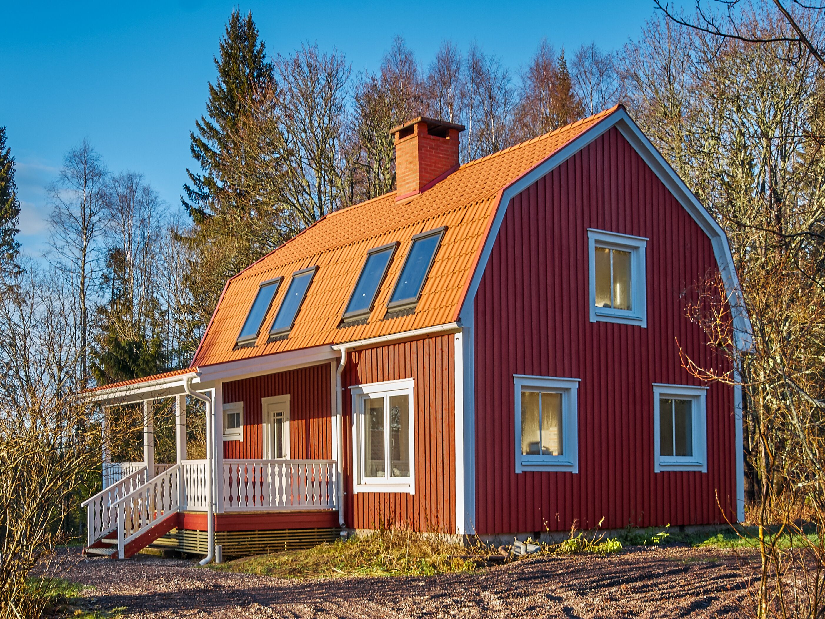 A red wooden house with a sloped roof and a covered porch.