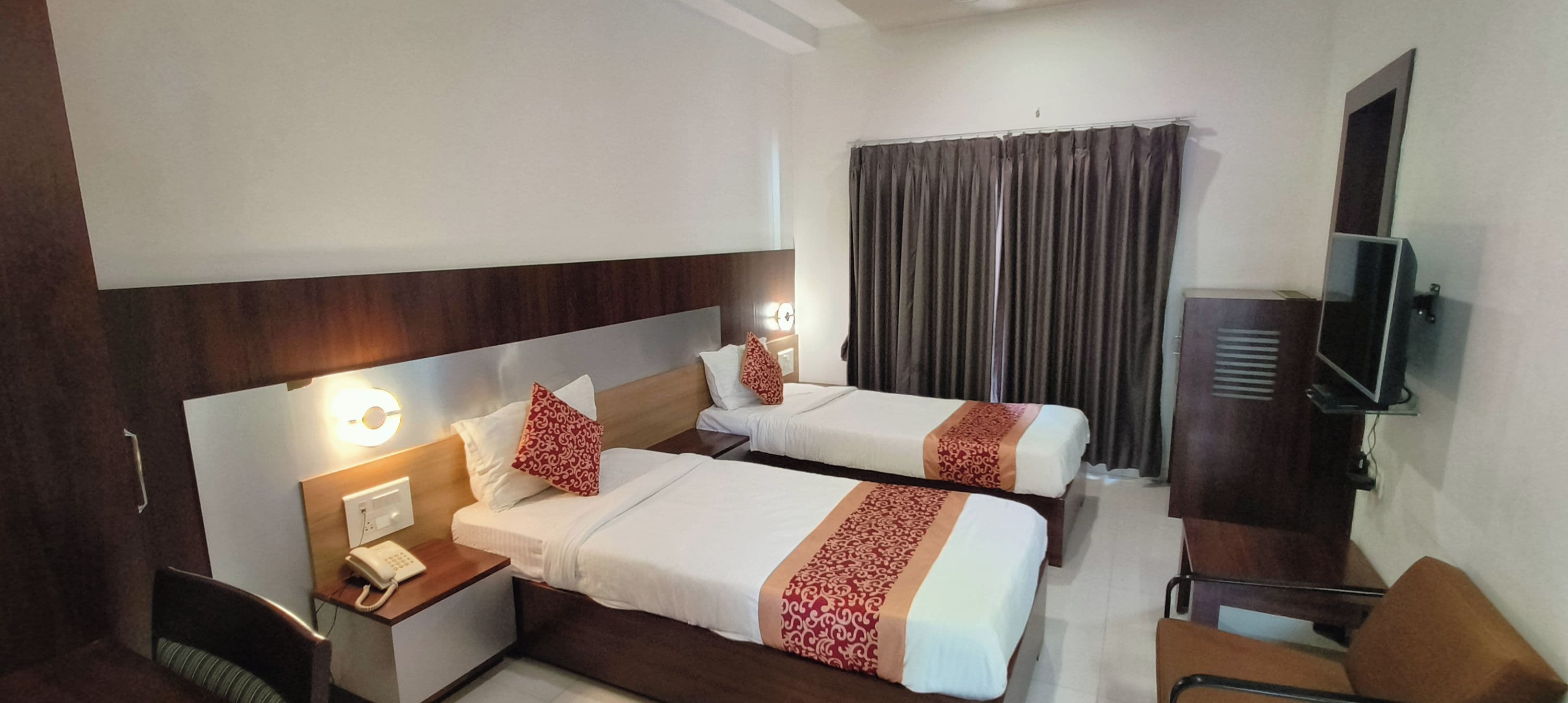 Une chambre d’hôtel avec deux lits, un bureau avec un téléphone, une télévision et une chaise.