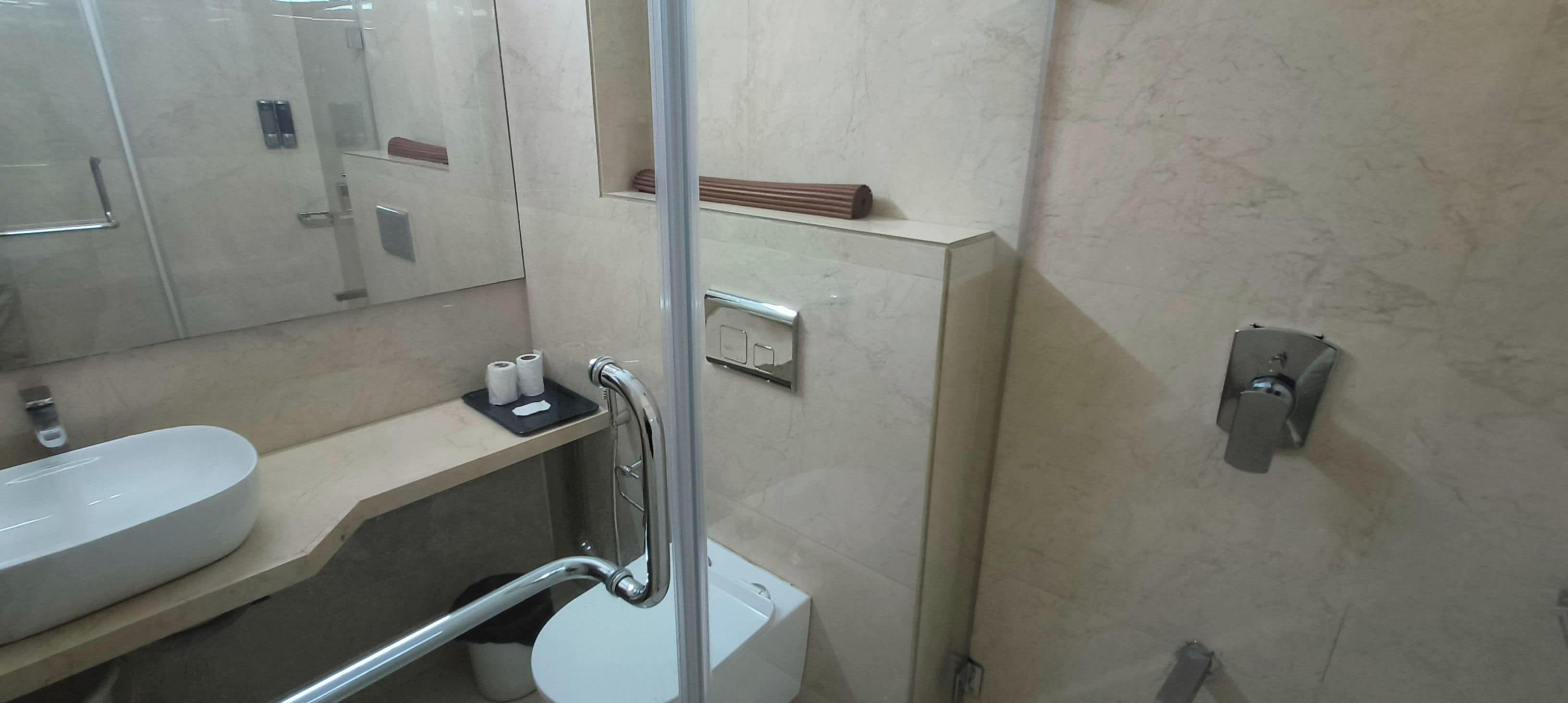 Un baño con un lavabo blanco, un espejo, un inodoro y una zona de ducha.