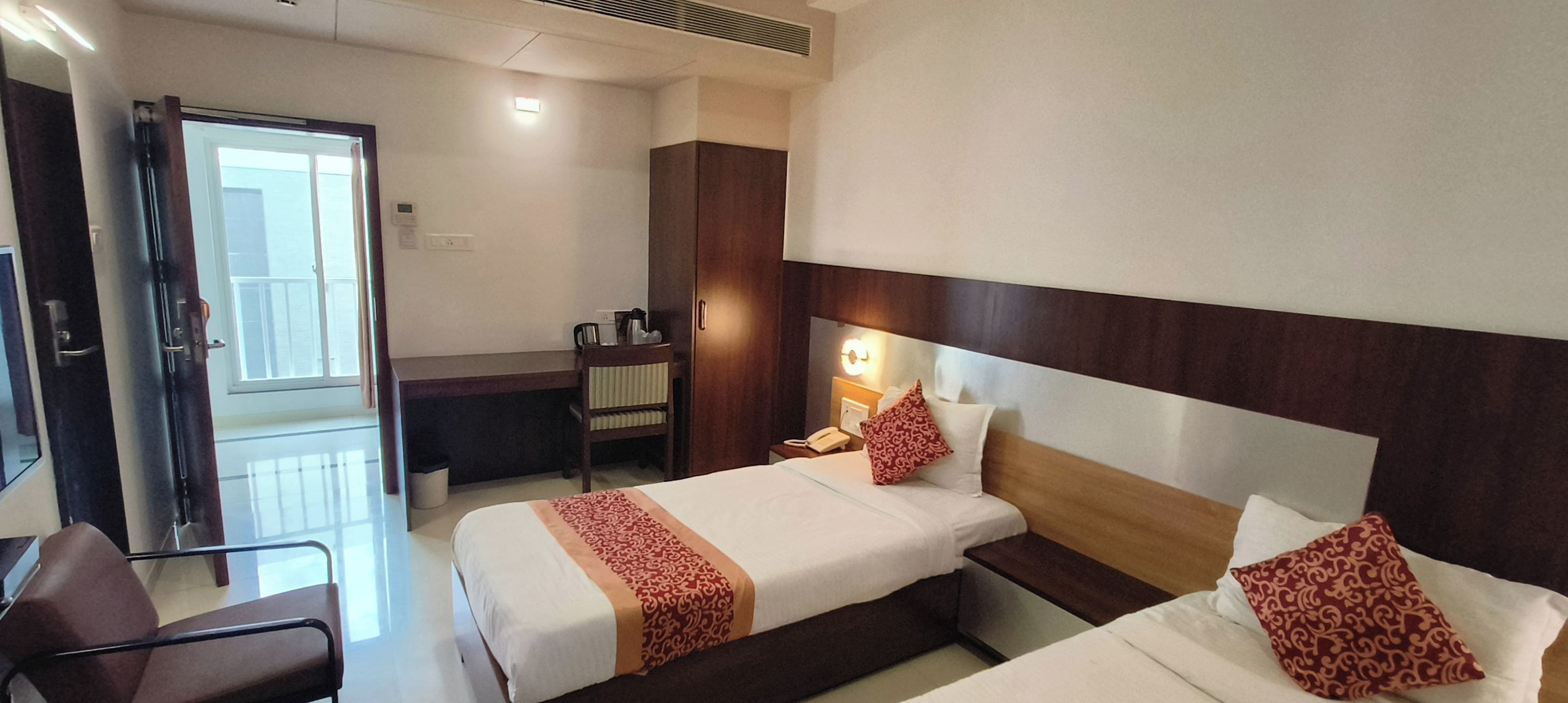 A hotel room with two beds, a desk, and a chair.