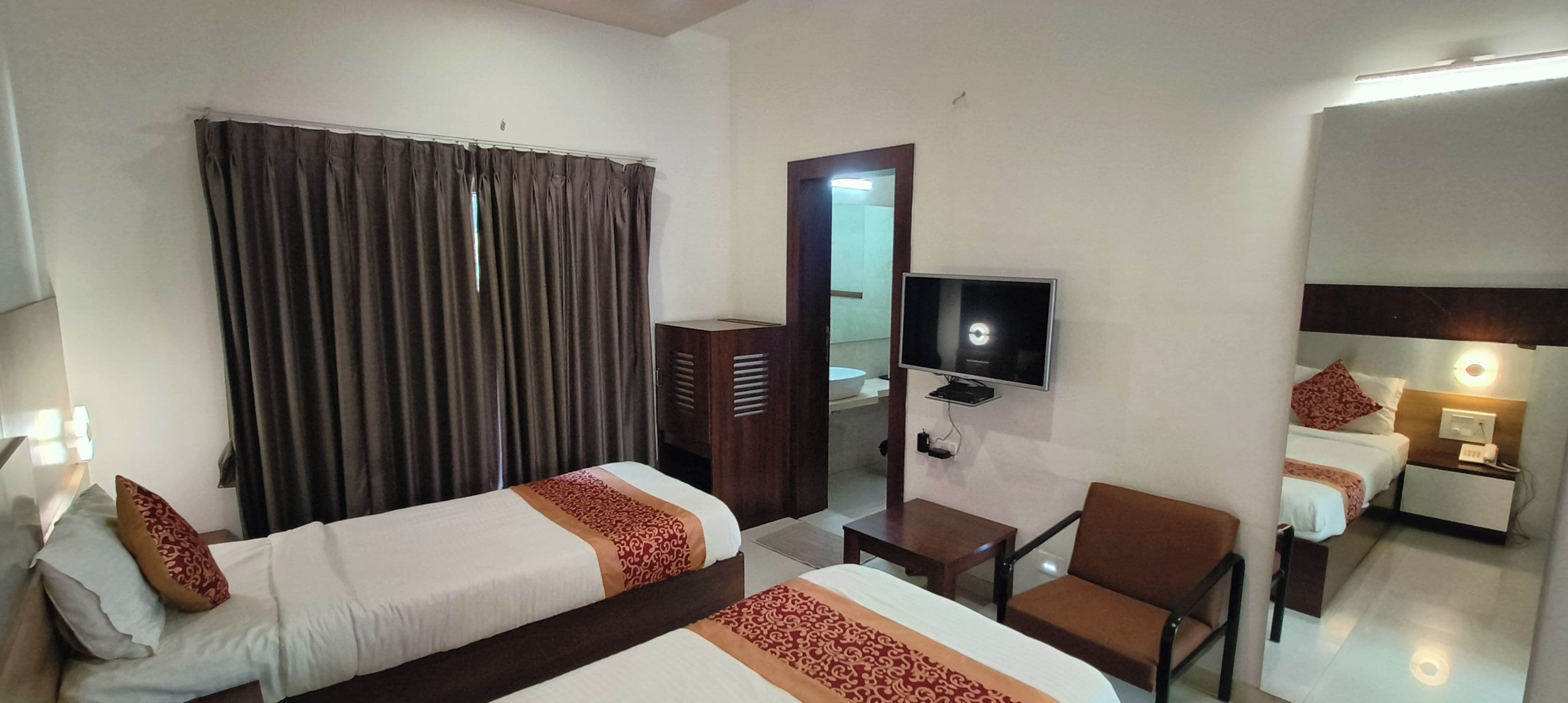 A hotel room with two beds, a television, a desk, and a chair.
