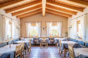 Enjoy meals in this spacious dining area with tables and chairs, surrounded by high ceilings and large windows.
