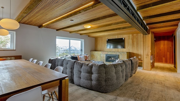 A spacious living area with a wooden ceiling, a large seating area, and a fireplace. - Le Chalets (Falls Creek)