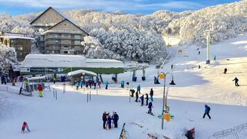 Estância de esqui com um edifício grande, teleféricos e paisagem coberta de neve.