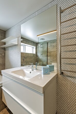 A modern bathroom with a large sink, a mirror, and a shower area. - Le Chalets (Falls Creek)
