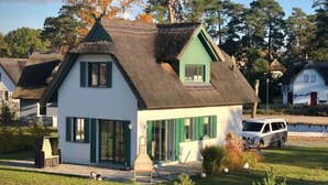 A house with a steeply pitched roof, a small porch, and a well-maintained lawn.