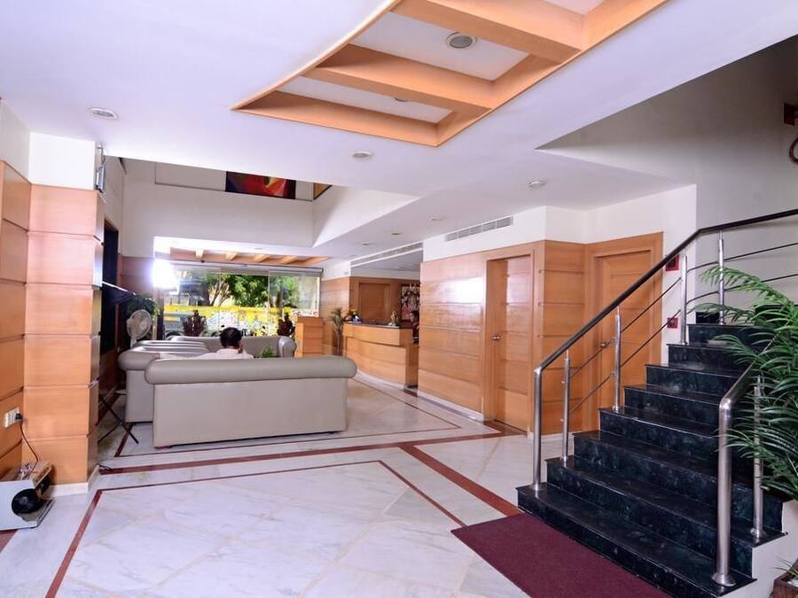 A spacious lobby with a reception desk, a staircase, and a seating area.