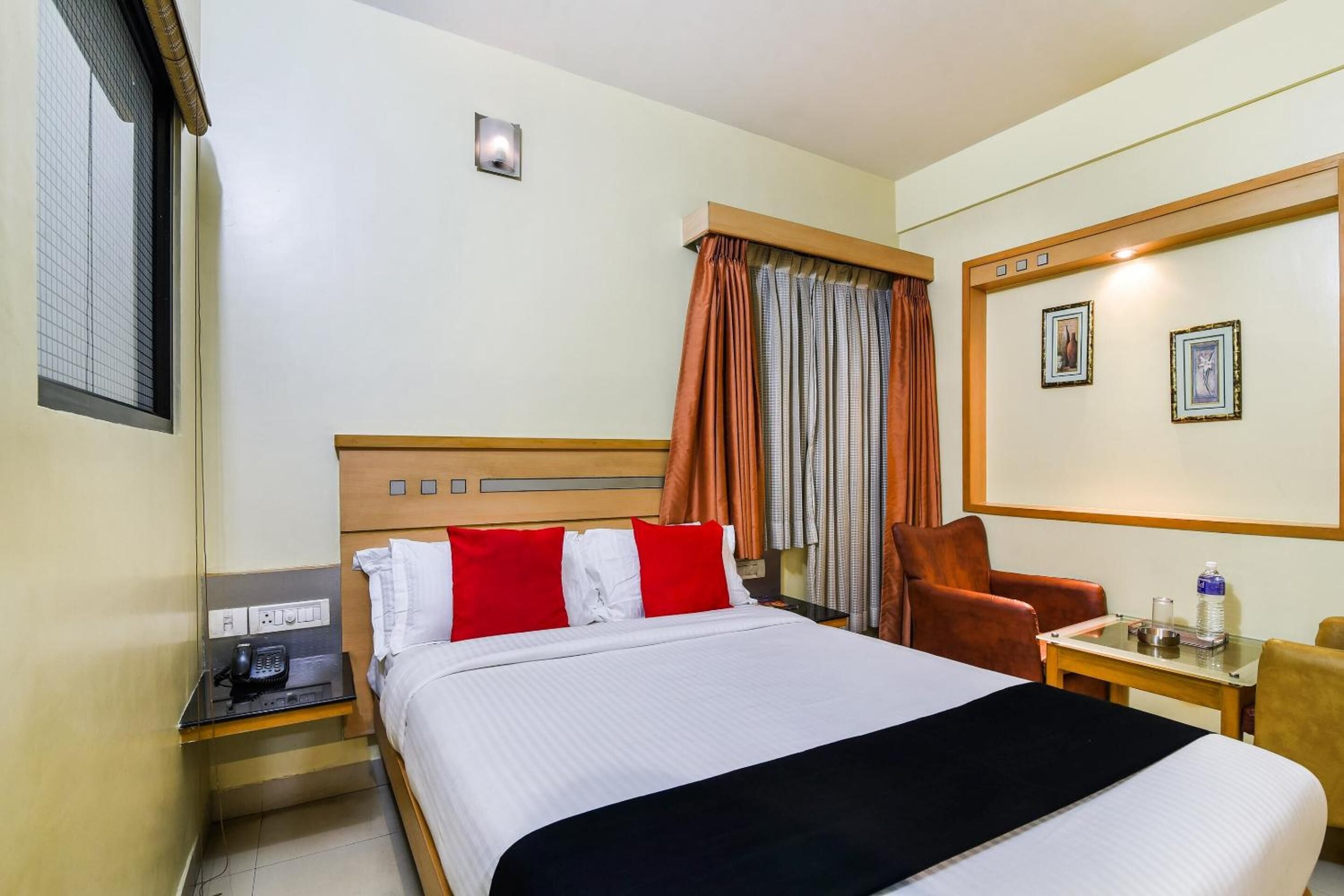 Habitación de hotel con cama, mesita de noche, una silla, una mesa y televisor montado en la pared.
