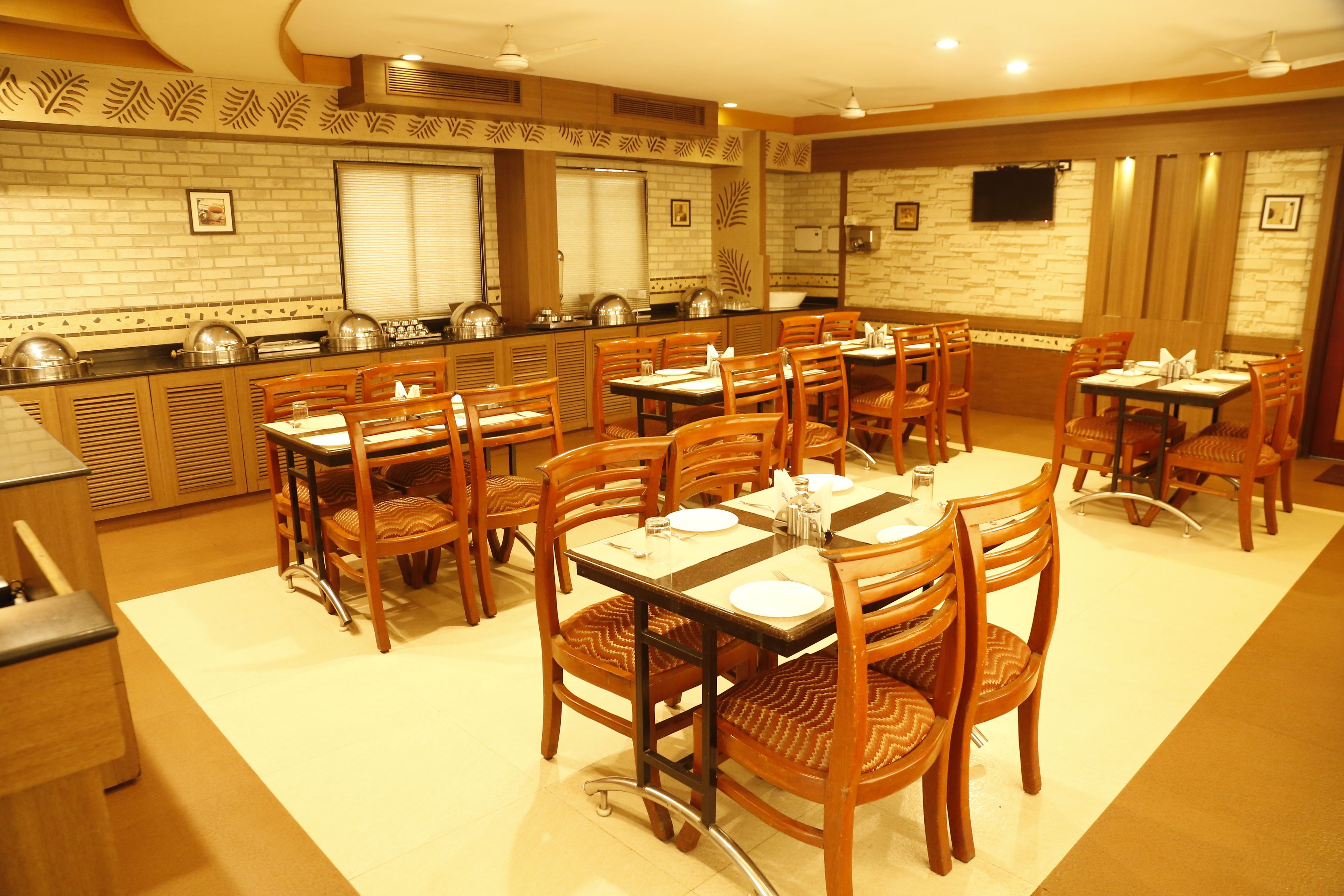 Comedor con varias mesas y sillas, con vajilla y una barra de buffet.